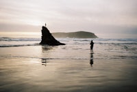 a person is standing in the water near a rock