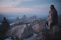 a woman standing on top of a mountain in cappadocia, turkey