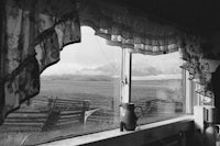 a black and white photo of a window with a view of mountains