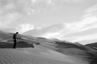 a man standing on a sand dune in black and white